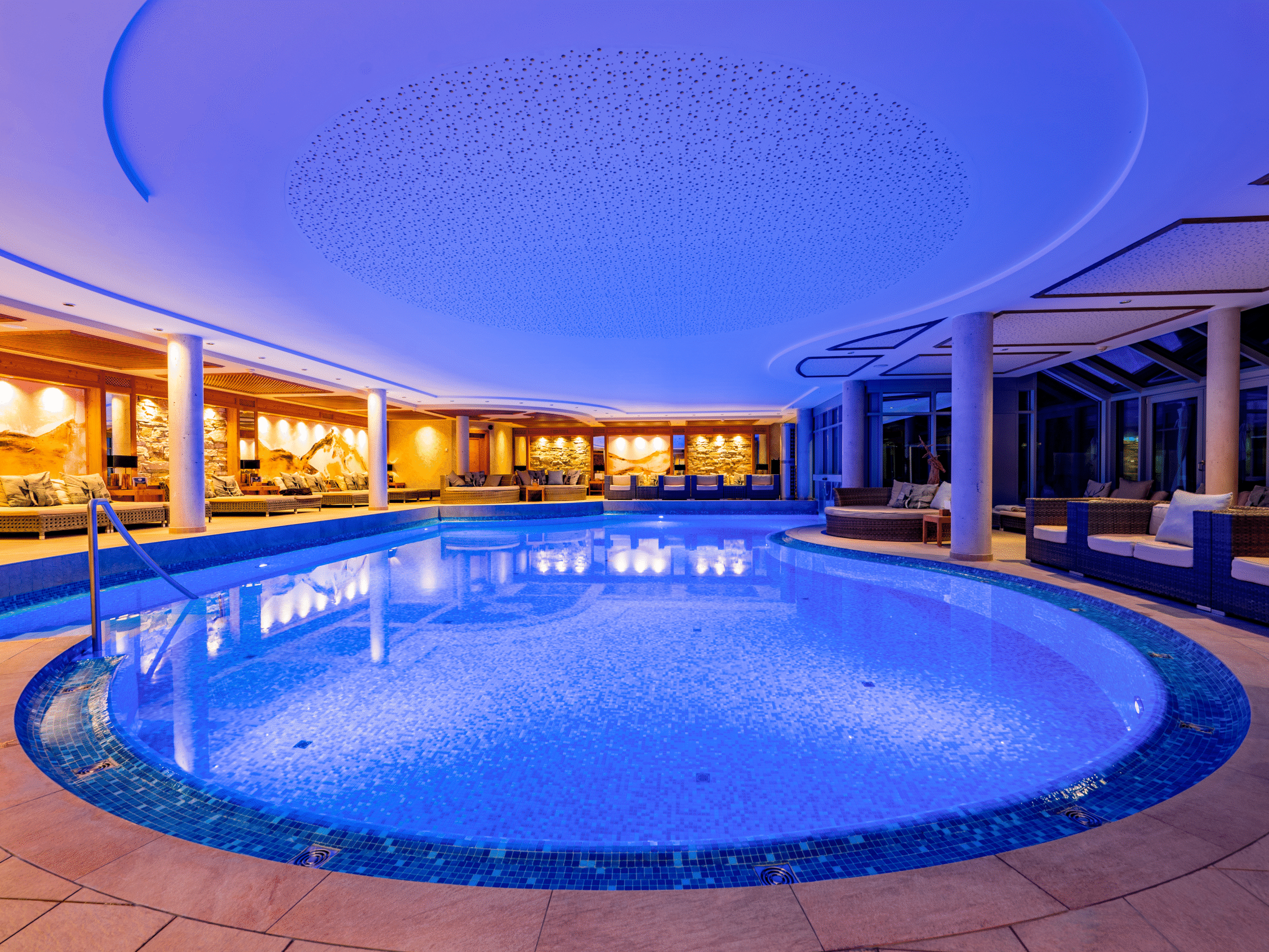 Beleuchteter Innenpool im 2000m² SPA Bereich im Meiser SPA Resort mit Liegebereich und alpiner Wandgestaltung