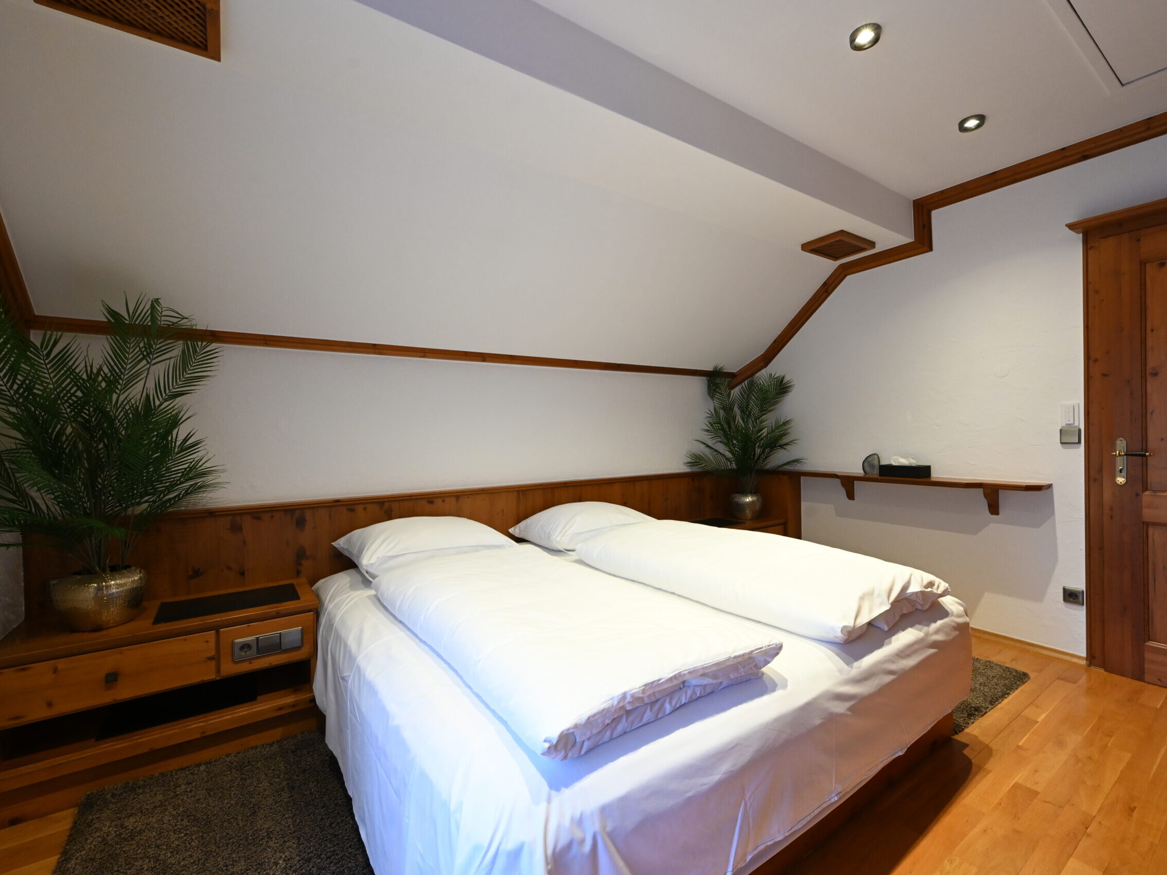 Schlafzimmer mit Doppelbett, Nachttischen und Holzverkleidung im Chalet-Stil.