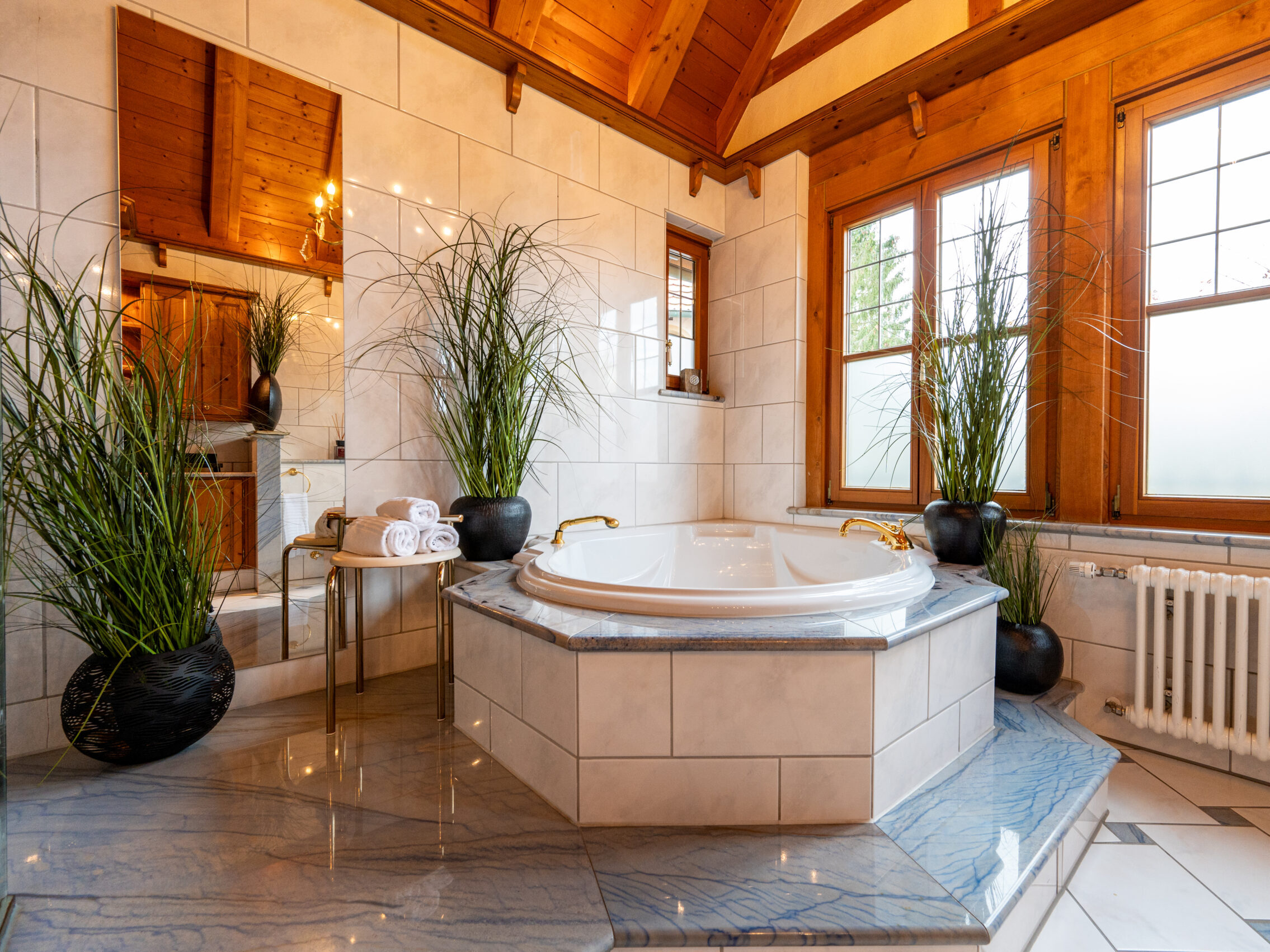 Nahaufnahme der eingelassenen Badewanne mit goldfarbenen Armaturen.