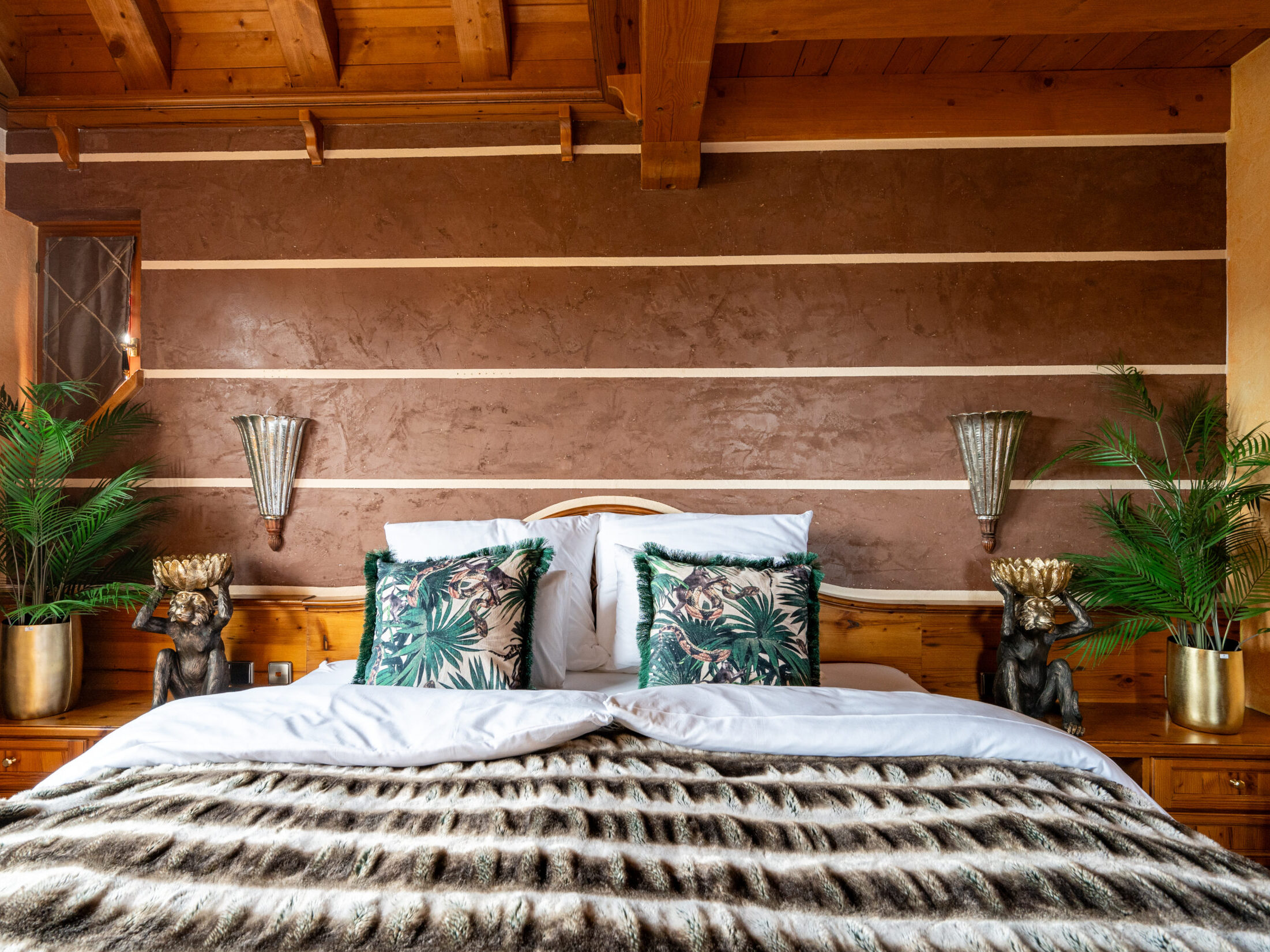 Gemütliches Schlafzimmer mit edler Bettwäsche, Holzelementen und Dekokissen.