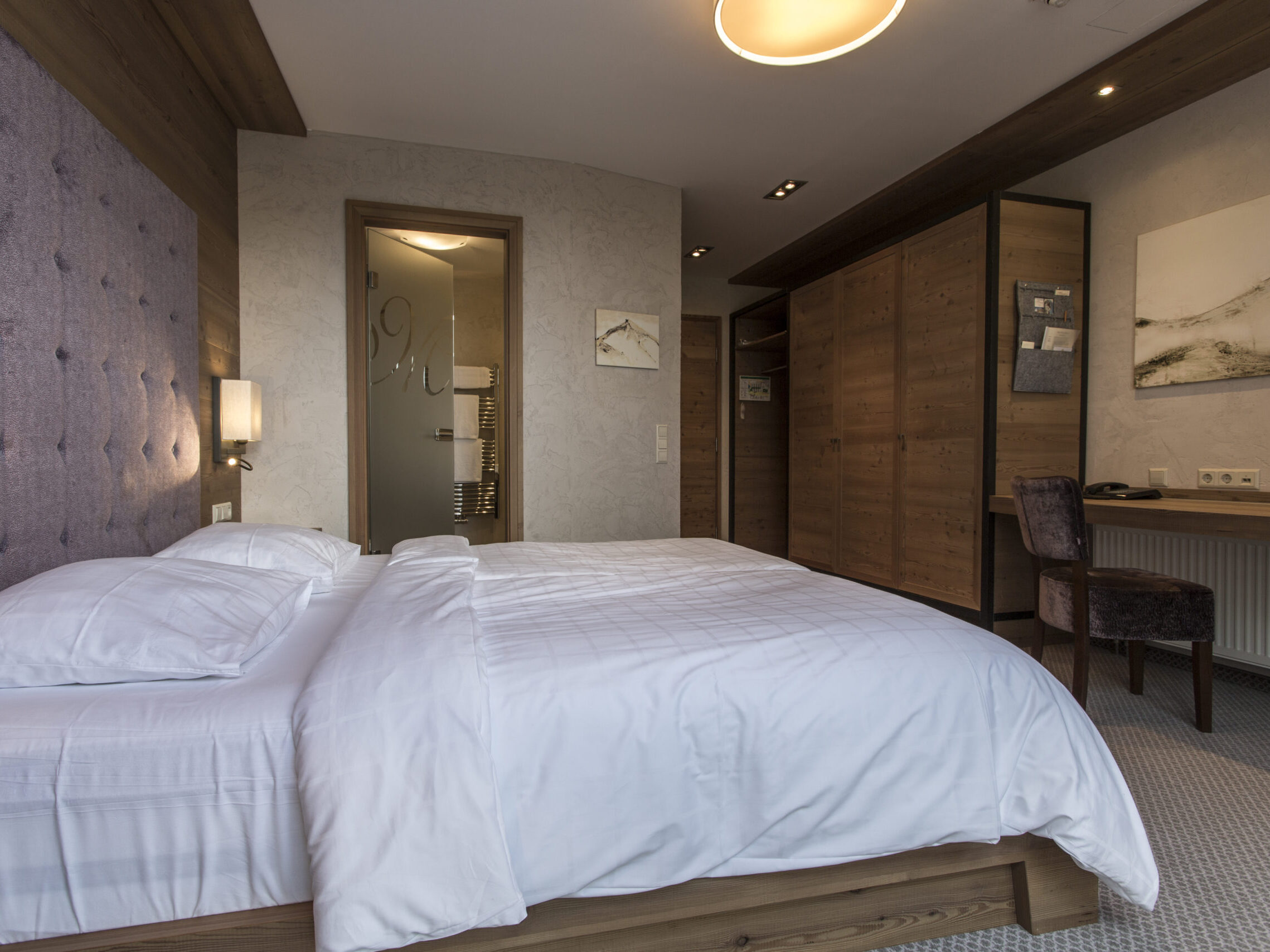 Im alpinen Stil eingerichtetes Hotelzimmer in der nähe vom Dinkelsbühl mit Doppelbett, Holzdesign, Schreibtisch und Zugang zum Badezimmer.