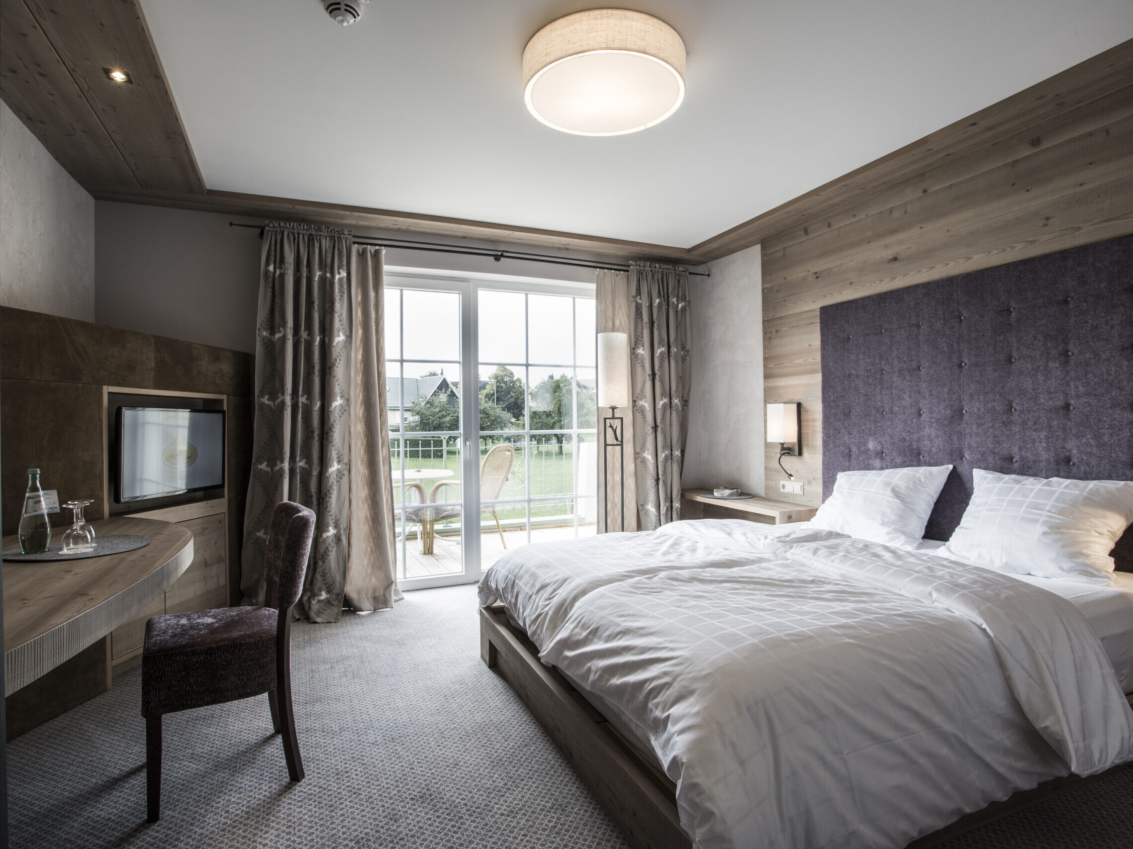 Comfort-Zimmer im alpinen Stil mit Doppelbett, Balkon und Blick auf die Natur im Meiser SPA Resort nahe Dinkelsbühl