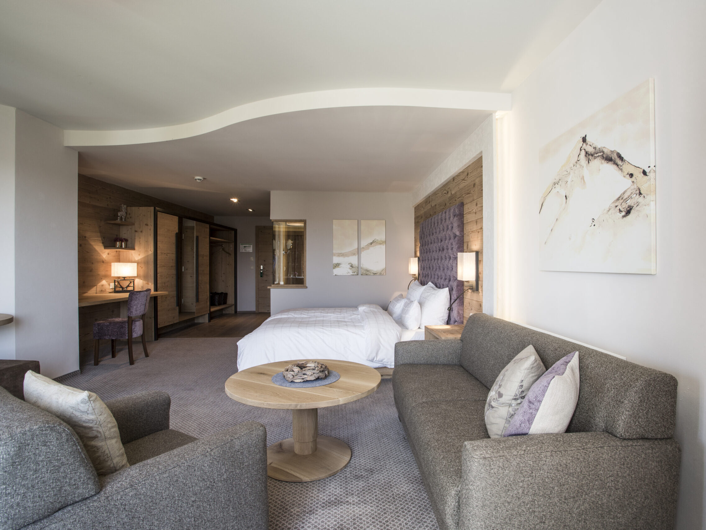 Großzügiges Zimmer mit Sofa, Schreibtisch und Balkon.