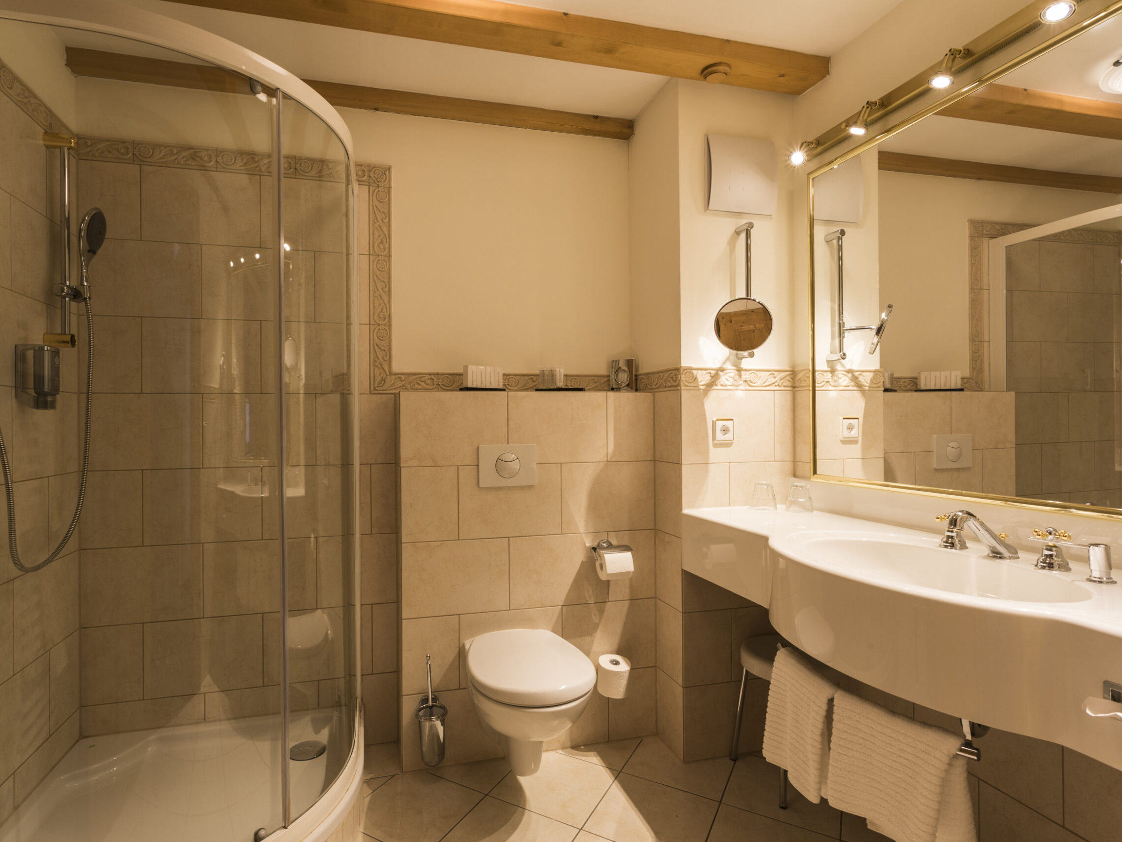 Ansprechendes Badezimmer mit Dusche, großem Spiegel und stilvoller Beleuchtung.