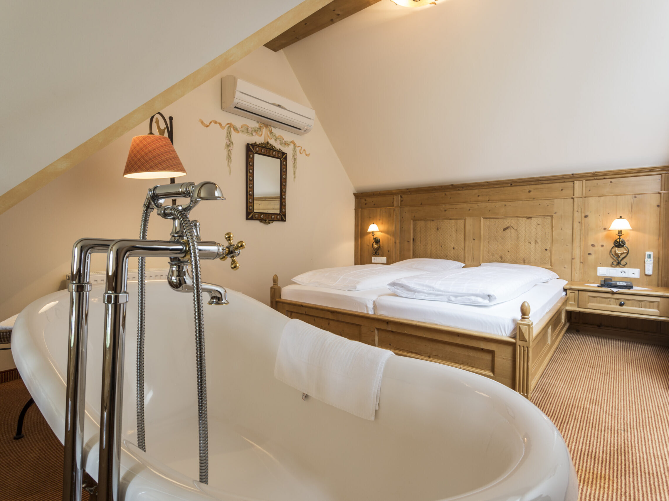 Premium Suite im alpinen Stil mit freistehender Badewanne und gemütlichen Doppelbett.