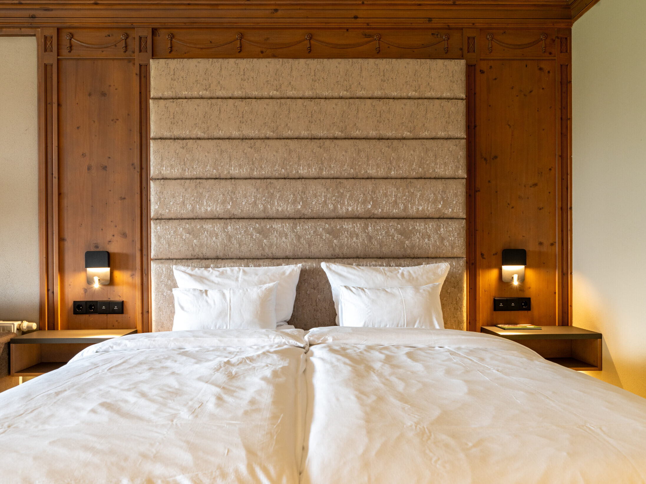 Schlafbereich im Superior Zimmer modern mit Doppelbett und Holzverkleidung im Meiser SPA Resort.